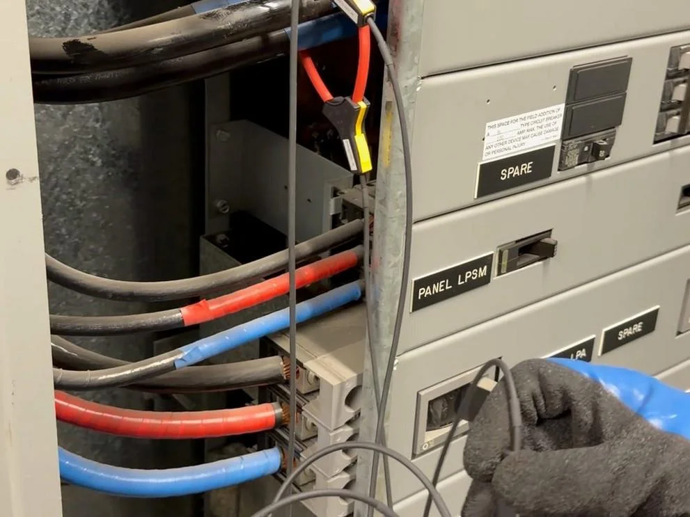 Temporary electrical measurement at a commercial building, photographed during AIM Dynamics audit fieldwork